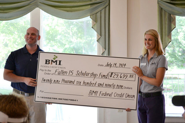 BMI director presenting large check to Fallen 15 director