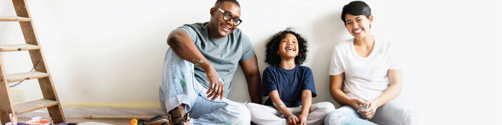 Family of three sitting down and smiling 