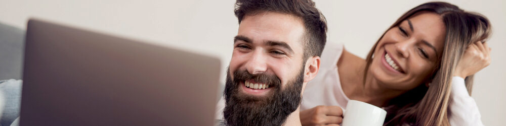 Man and woman smiling reviewing files on a laptop