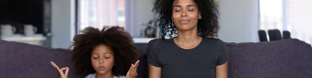 mother and daughter meditating on couch