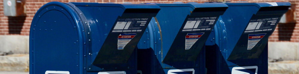 three blue USPS mailboxes