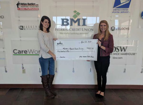 bmi fcu charitable giving director presenting a check to charity