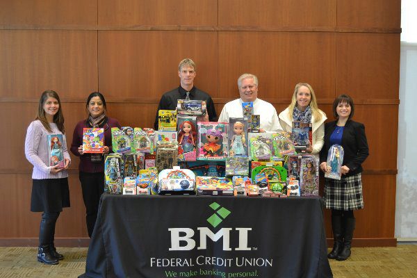 bmi fcu employees posing with a table of donated toys for children