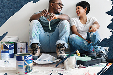 couple smiling on the floor with paint supplies