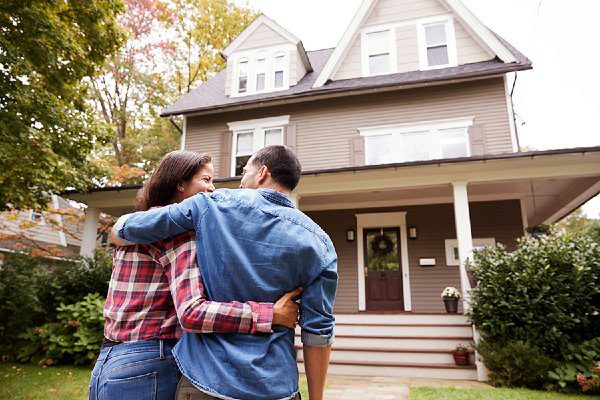 couple with arms around eachother in front of home