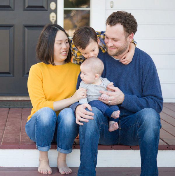 family smiling on porch