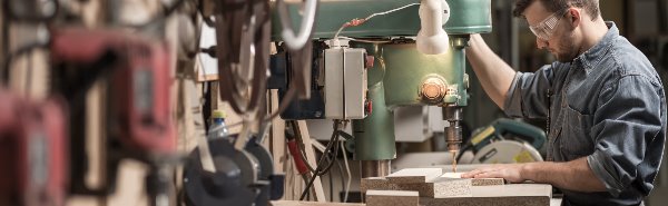 man in shop using power drill