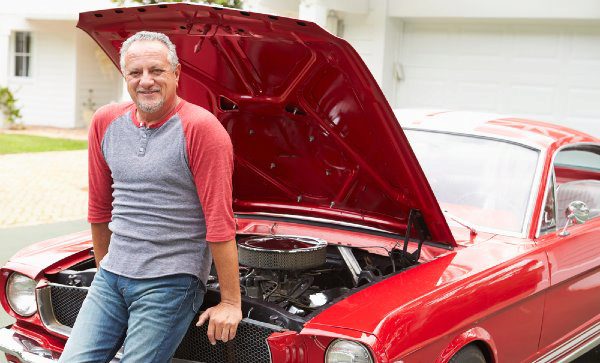man leaning on red car with hood open